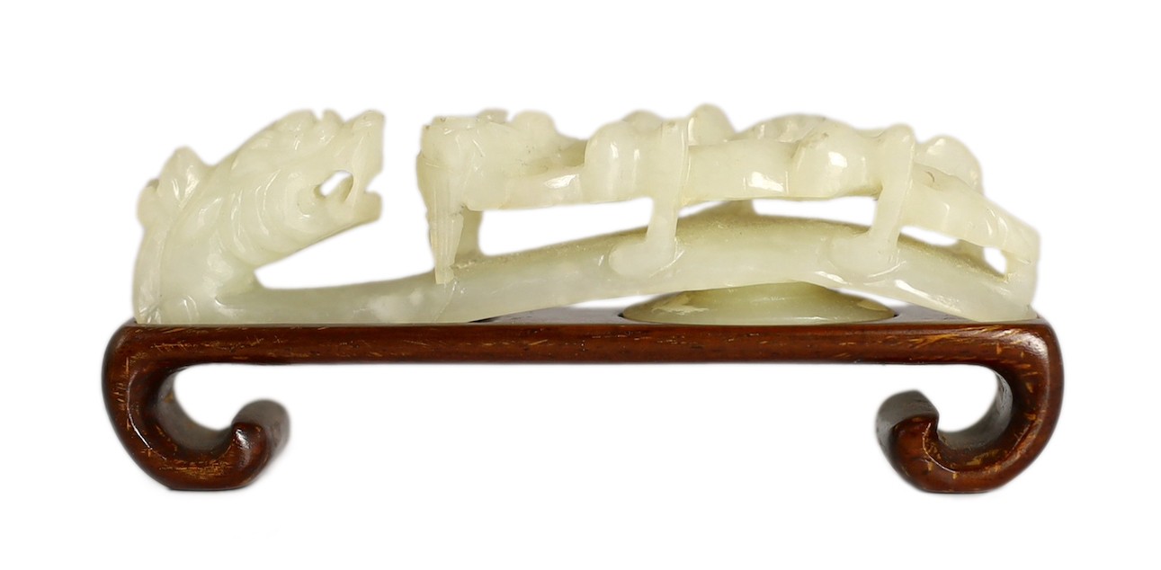 A Chinese white jade ‘dragon’ belt hook, 19th century, 9.4cm long, wood stand